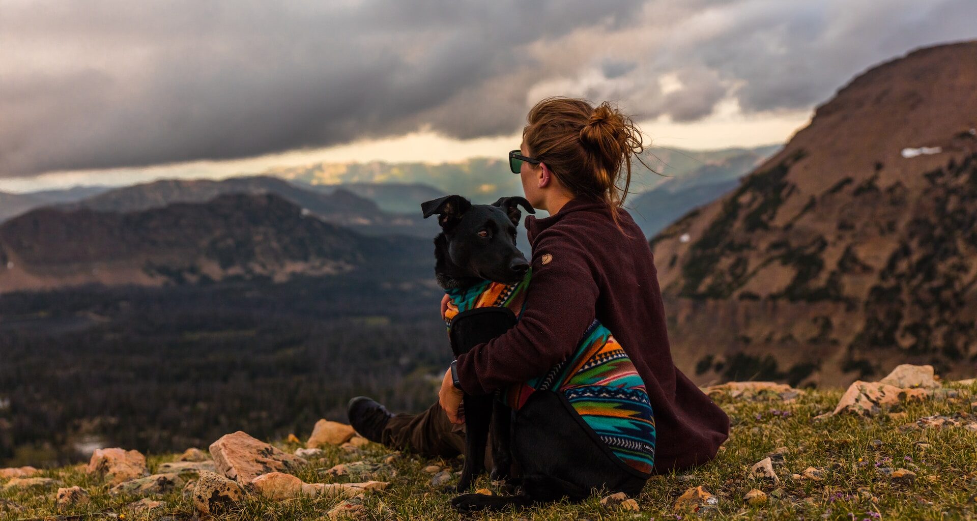 pies ze swoją panią, siedzą na trawie w górach